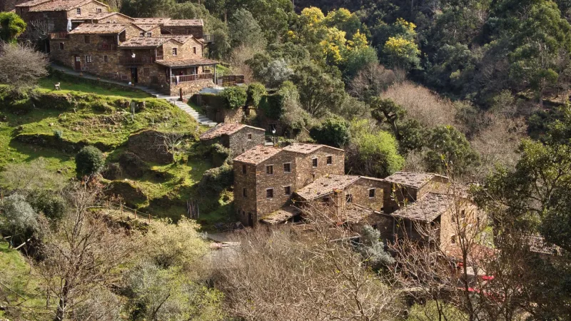 Vista das casas de xisto da aldeia de Talasnal, na Serra da Lousã, rodeadas pela paisagem verdejante.