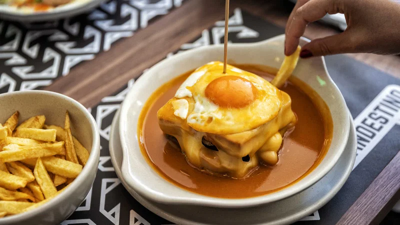 Francesinha servida com batatas fritas